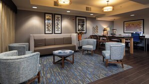 A hotel lobby with a sofa, armchairs, a coffee table, and a dining area with a table and chairs. - Holiday Inn Express Castro Valley - I-580 by IHG (Castro Valley)