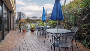 An outdoor patio with metal chairs and tables, surrounded by potted plants and a metal fence. - Holiday Inn Express Castro Valley - I-580 by IHG (Castro Valley)