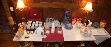 A table set with various food items, glassware, and a coffee machine, indicating a self-service breakfast area.