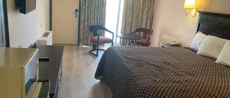 Una habitación de hotel con una cama, un escritorio, una silla, una lámpara y un teléfono.