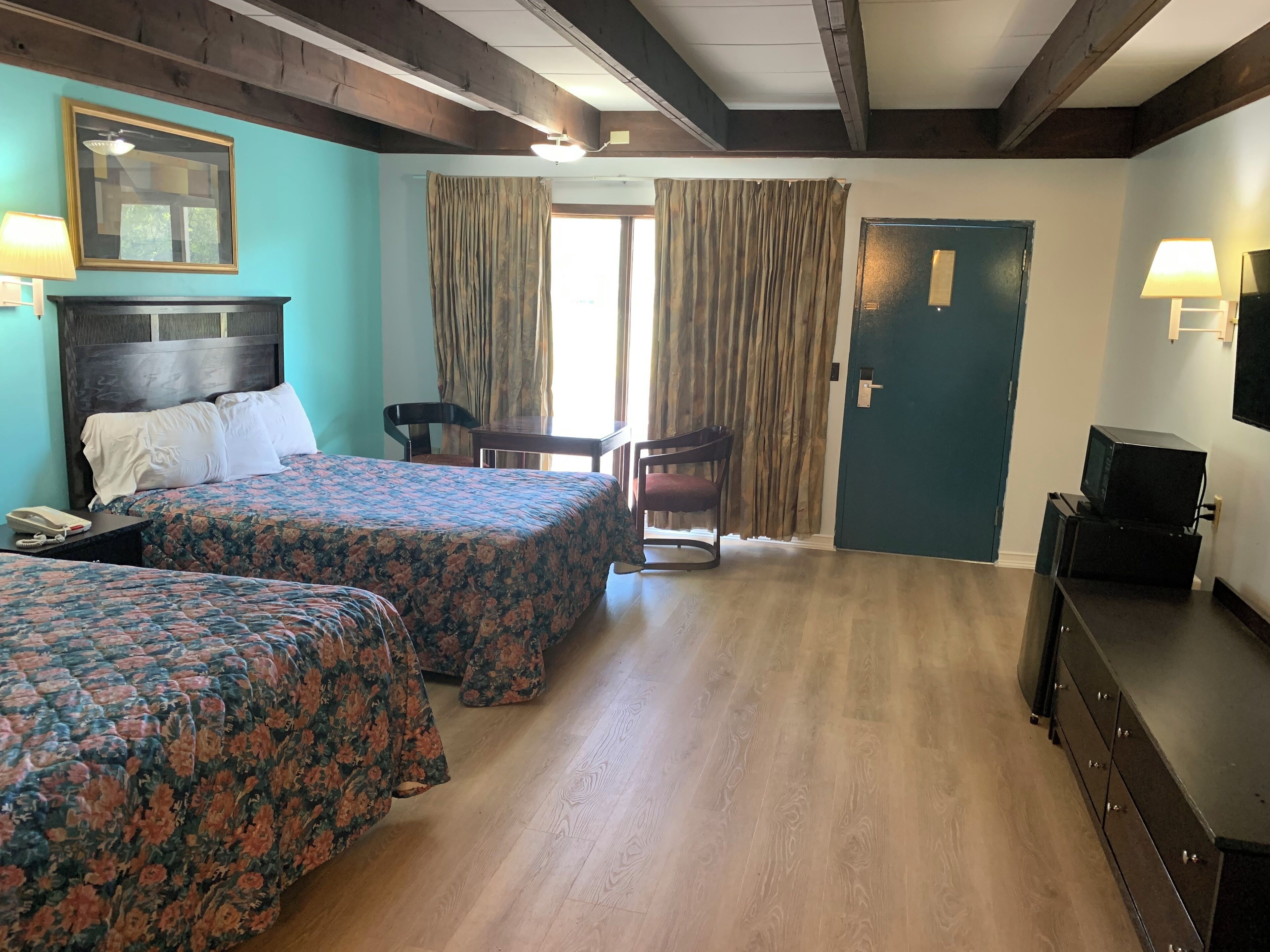 Una habitación de hotel con dos camas, un escritorio, una silla, un televisor y una puerta.