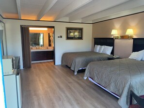 A hotel room with two beds, a desk, a mirror, and a bathroom visible through an open door. - Tollway Inn of Beloit (South Beloit)