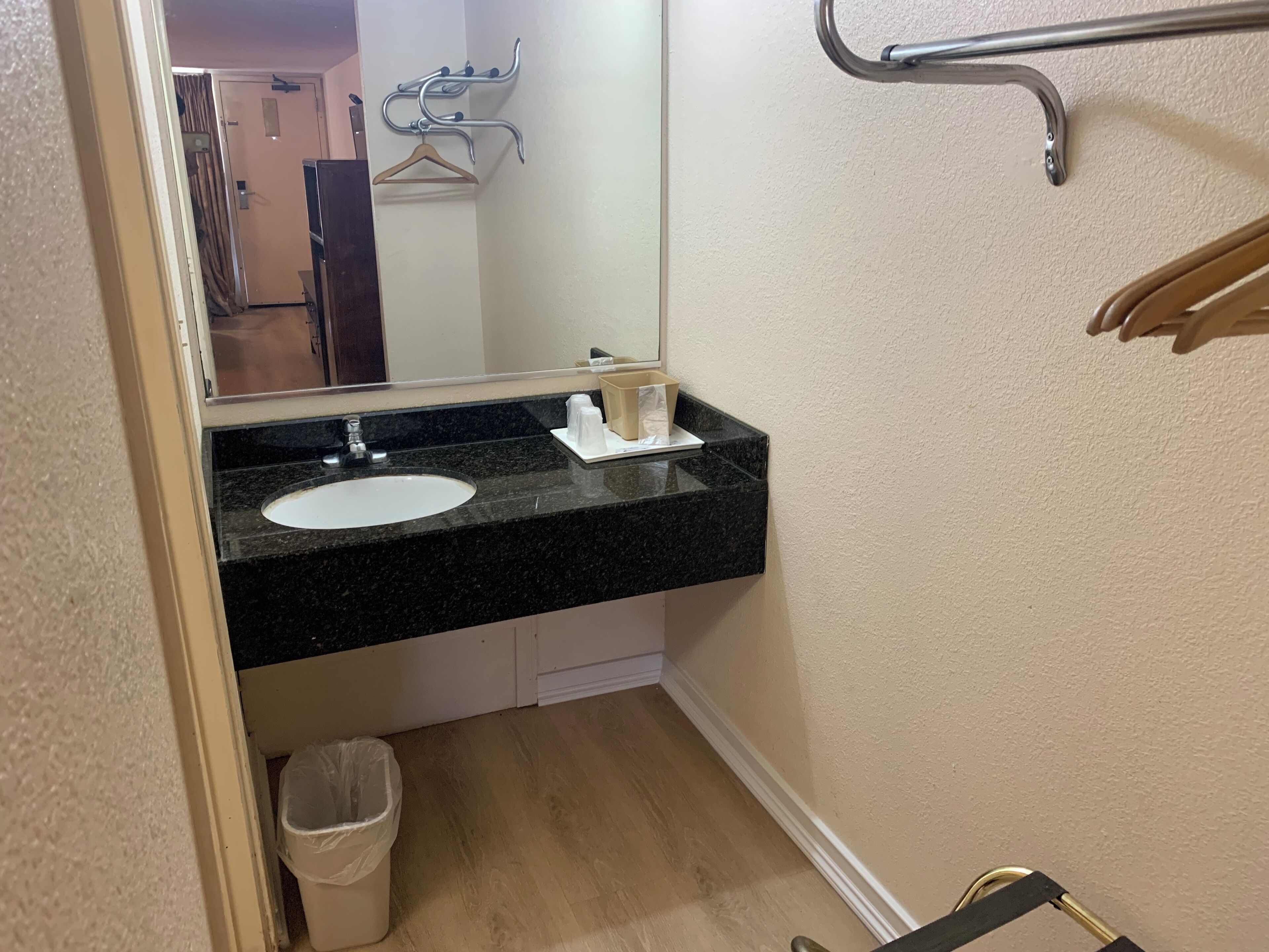 A bathroom with a black granite countertop, a white sink, a mirror, and a towel rack.