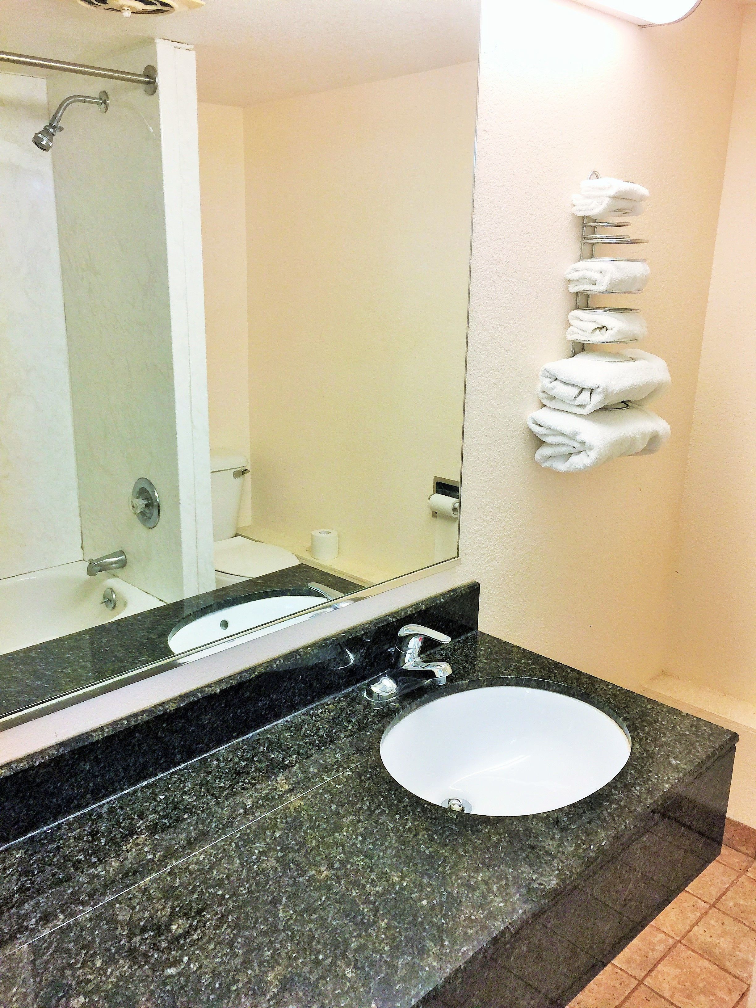A bathroom with a sink, mirror, and towel rack.