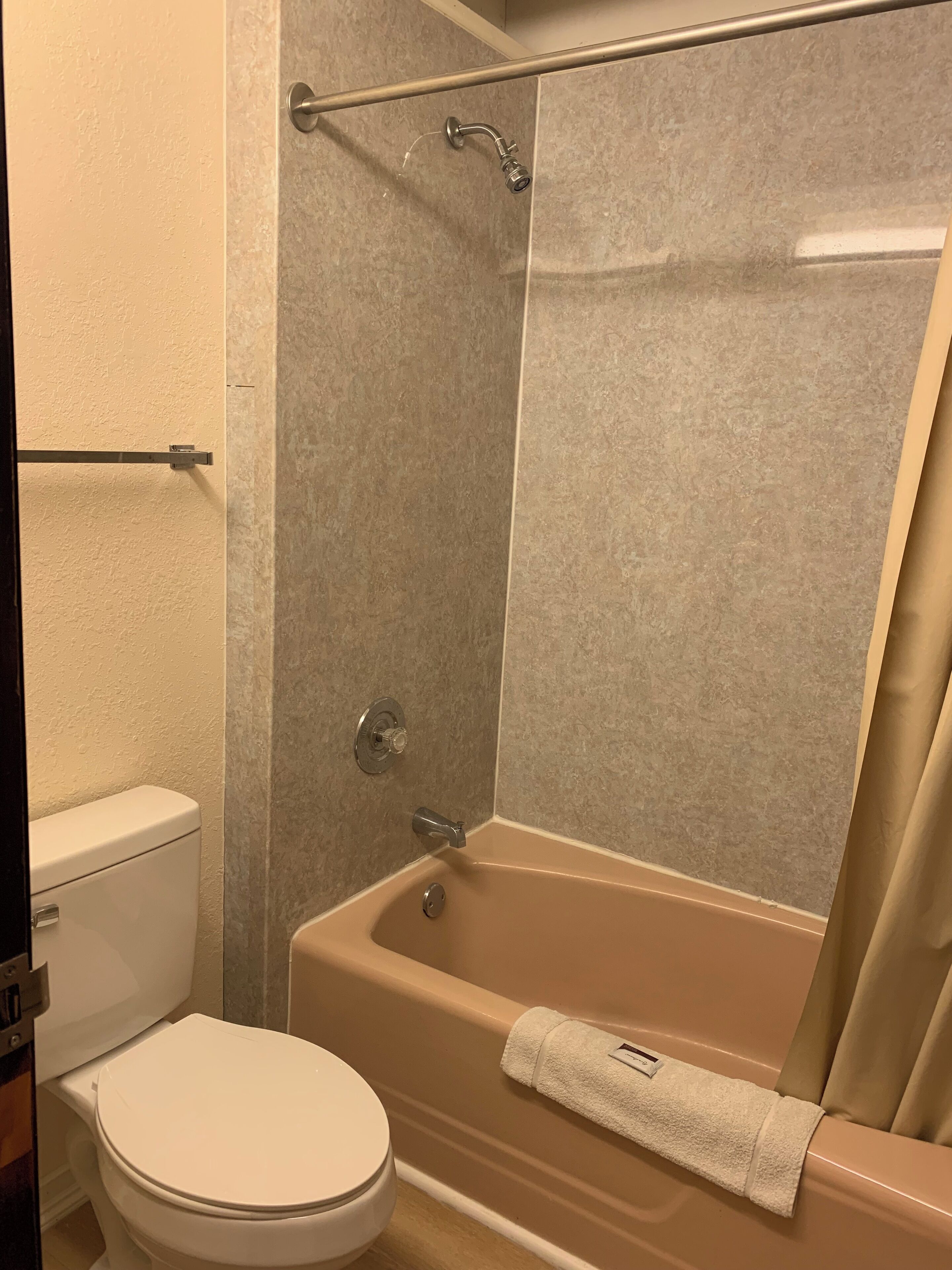 A bathroom with a toilet, a shower with a glass door, and a bathtub with a towel.