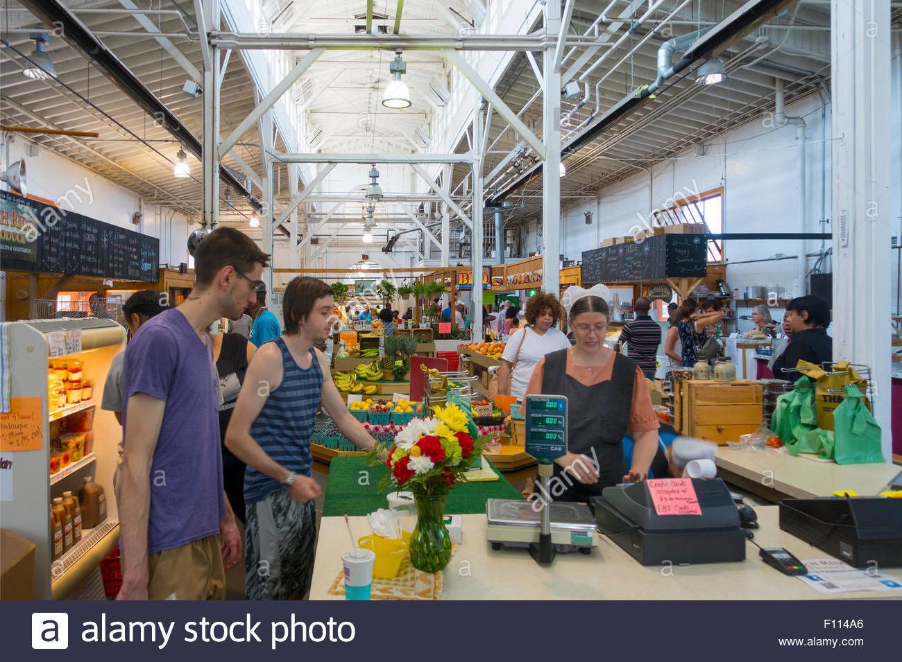 A busy indoor market with various stalls and shoppers.