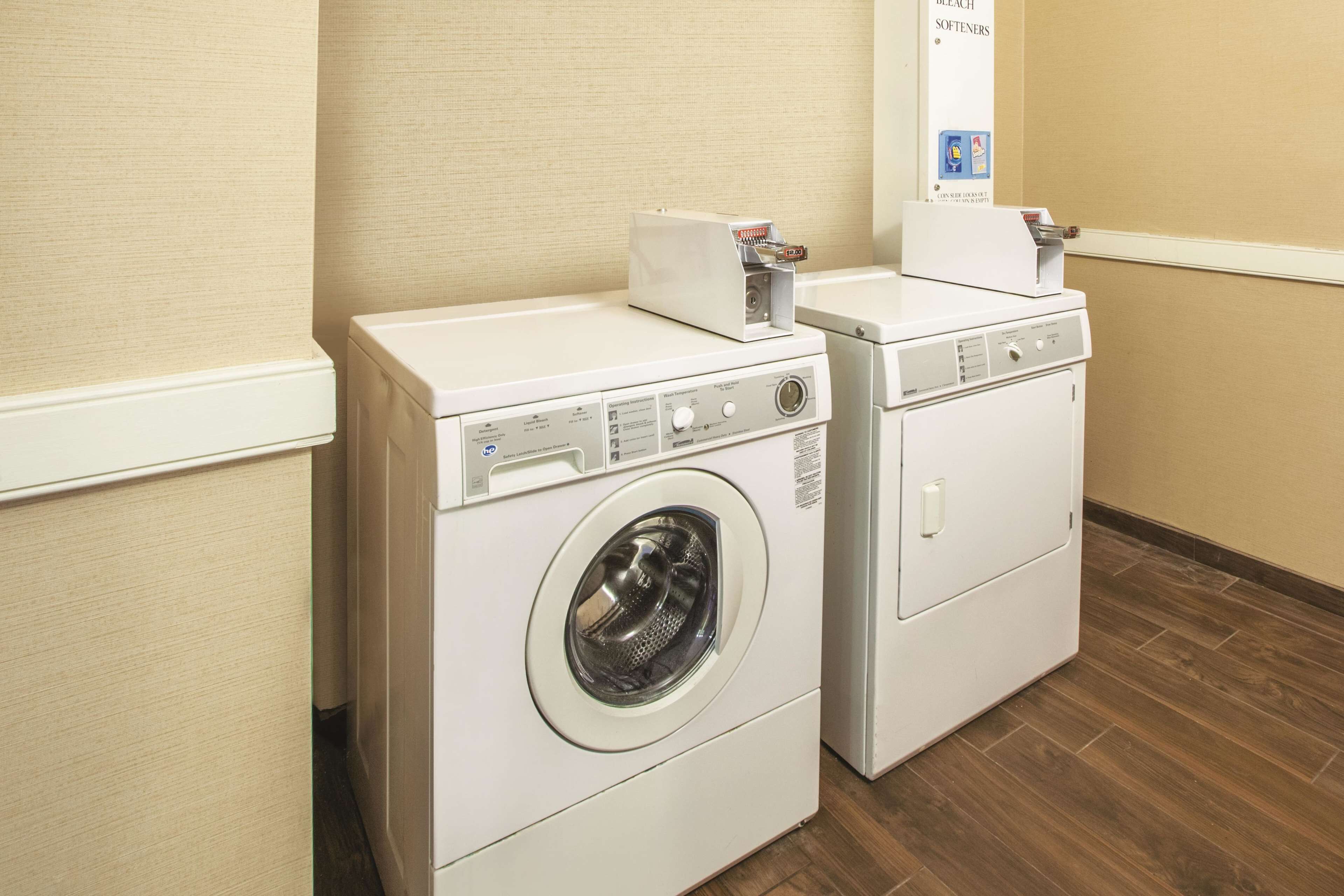 A laundry area with two white washing machines and a wall-mounted dryer.