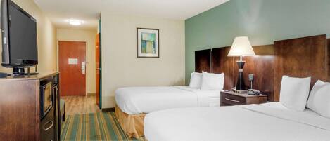 Habitación de hotel con dos camas, un televisor, un escritorio y una lámpara.
