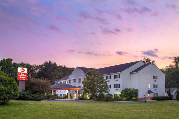 Stately hotel with a traditional facade, surrounded by lush lawns and mature trees.