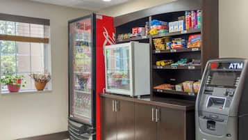 A vending machine, a refrigerator, and shelves stocked with snacks and beverages.
