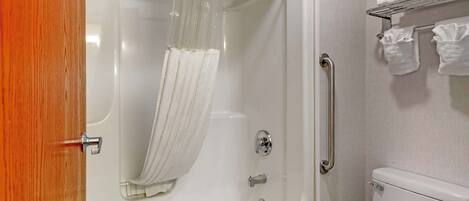A bathroom with a bathtub, toilet, and a towel rack with towels.