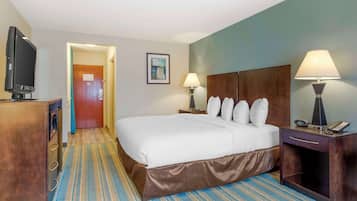 Une chambre d’hôtel avec un grand lit, deux lampes de chevet, une télévision, un bureau et une porte donnant sur une autre pièce.