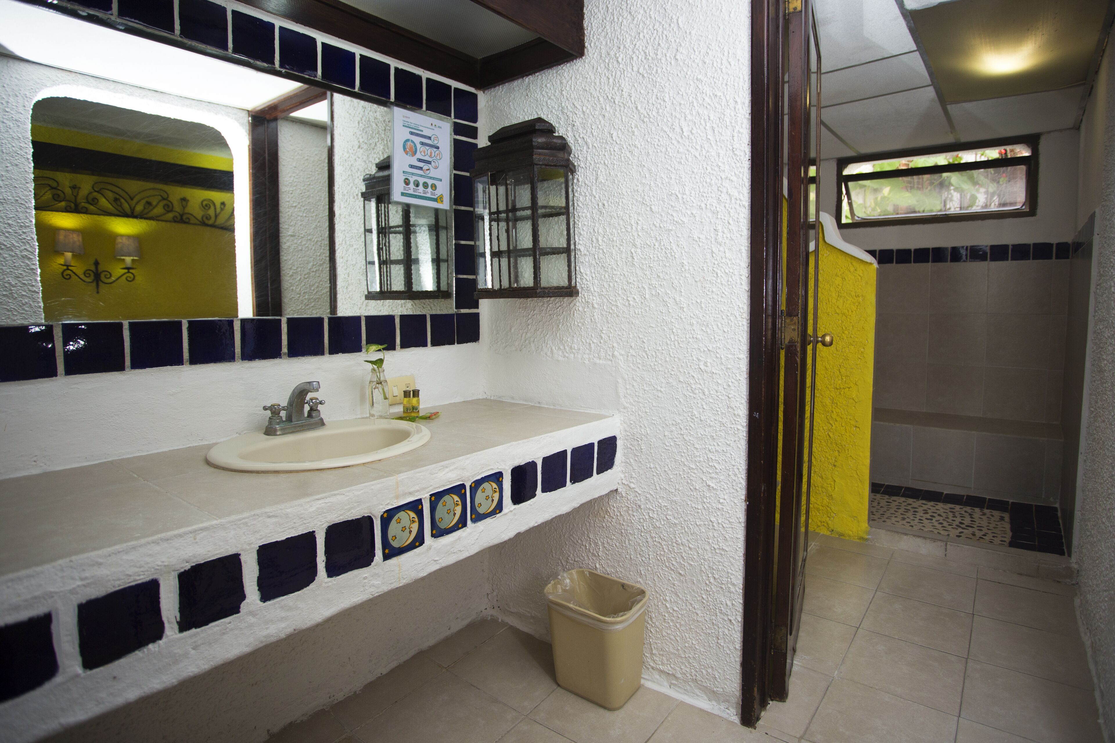 Une salle de bain avec un lavabo blanc, un miroir et un espace douche.