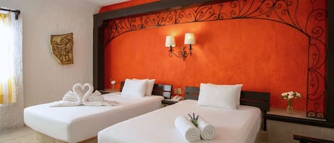 A hotel room with two beds, a decorative wall, a small table, and a vase with flowers.