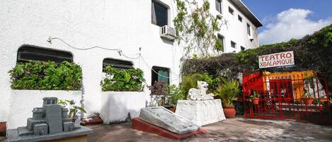 A courtyard with a white building, a red gate, and a sign reading "TEATRO XBALAMQUE".