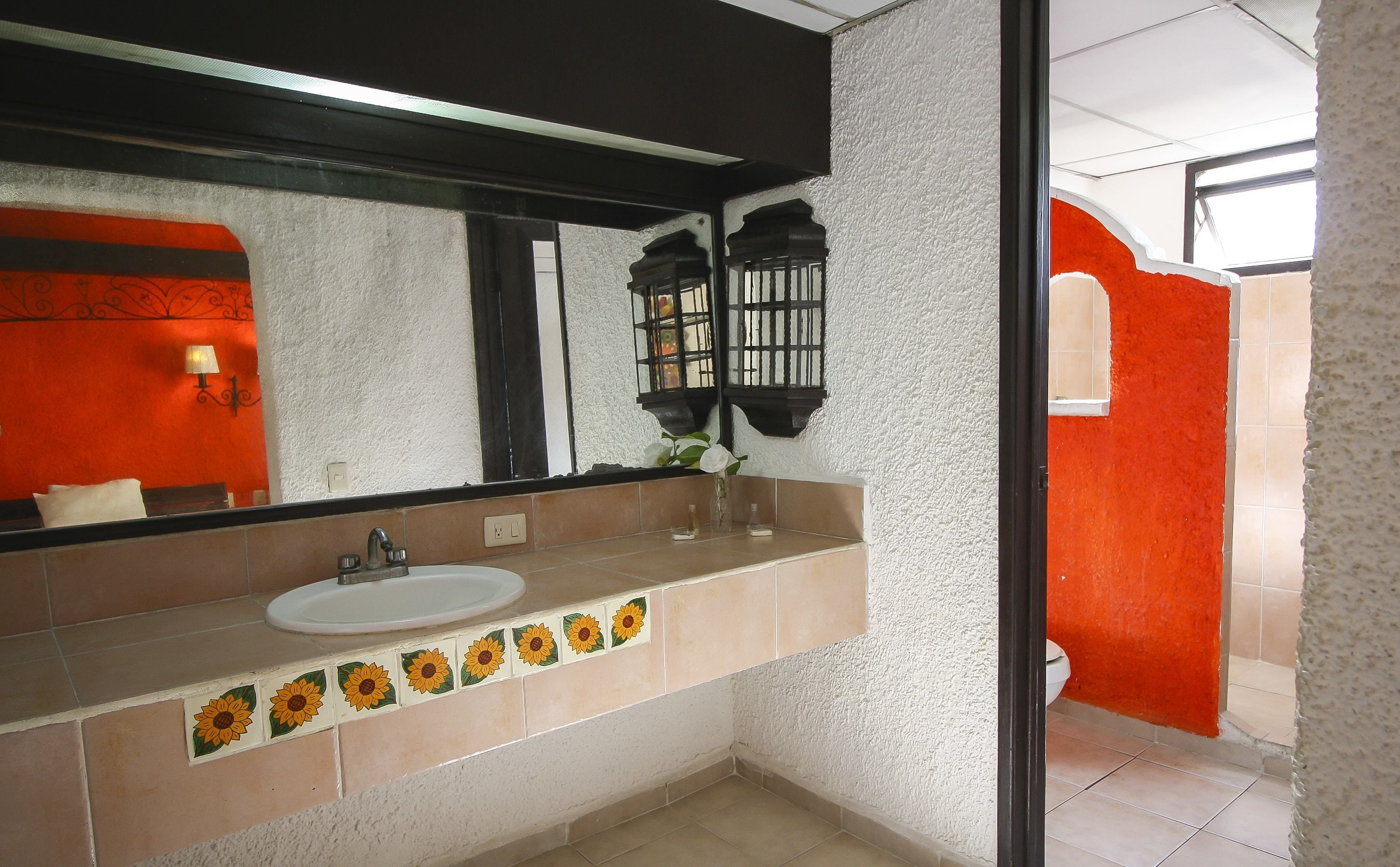 A bathroom with a white sink, a mirror, and a window with a view of the outside.
