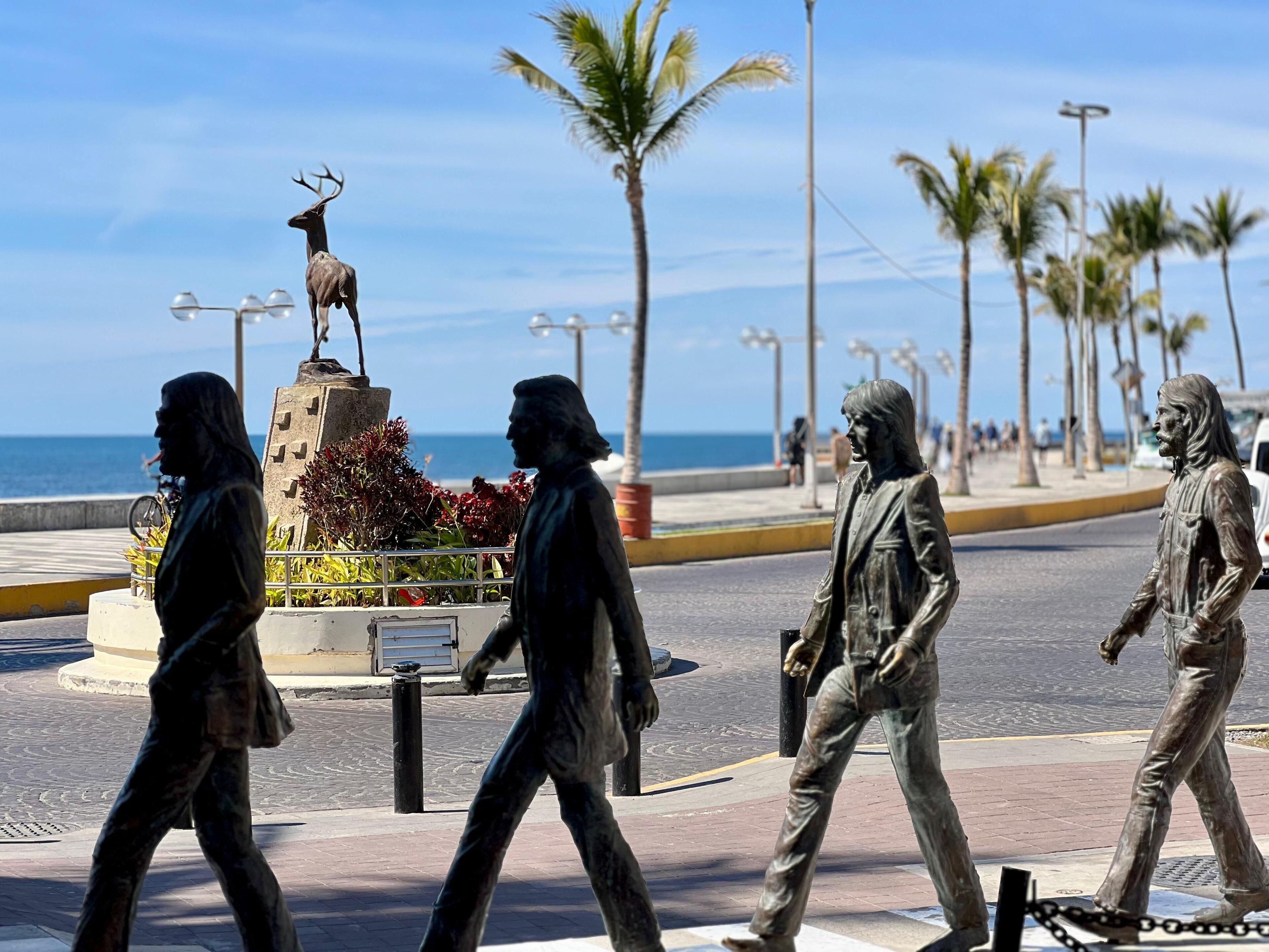 A statue of a man in a suit walking on a sidewalk.