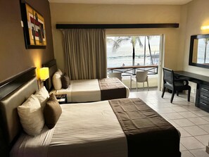 A hotel room with two beds, a desk, and a balcony with a view of the sea. - Hotel La Siesta Malecón (Mazatlán)