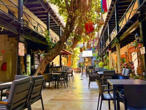 An indoor dining area with tables and chairs, a staircase, and hanging plants. - Hotel La Siesta Malecón (Mazatlán)