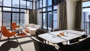 A modern hotel room with large windows, a dining area, and a seating arrangement. - Adina Citylife Auckland (Auckland)