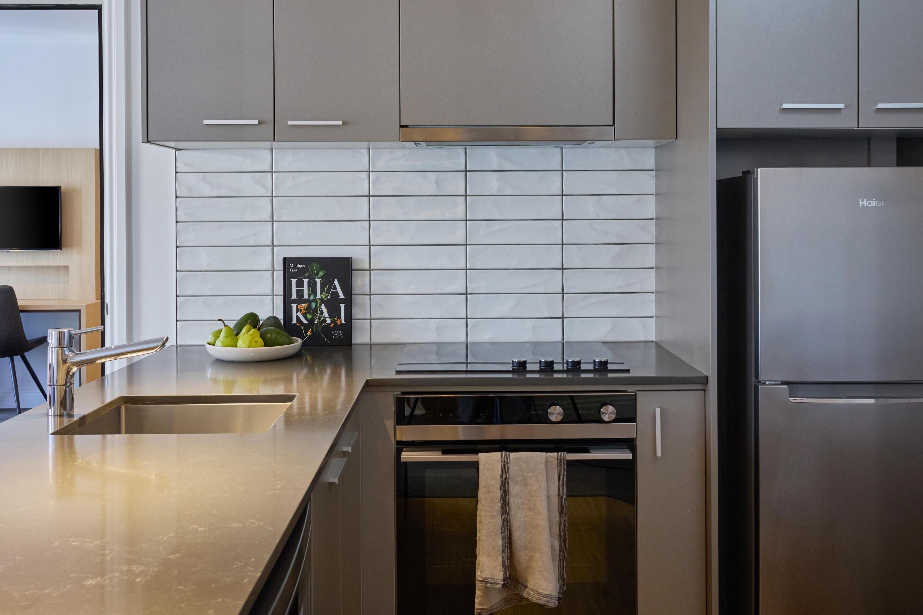 A modern kitchen with stainless steel appliances, a tiled backsplash, and a minimalist design.