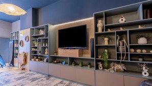 Un salón moderno con un televisor de pantalla plana grande, estanterías empotradas con objetos decorativos y un suelo estampado.