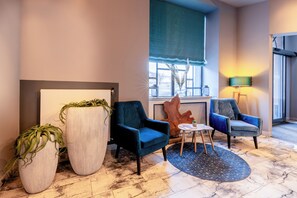 Relax in a cozy seating area with comfortable armchairs and a sofa, surrounded by lush greenery and natural views.