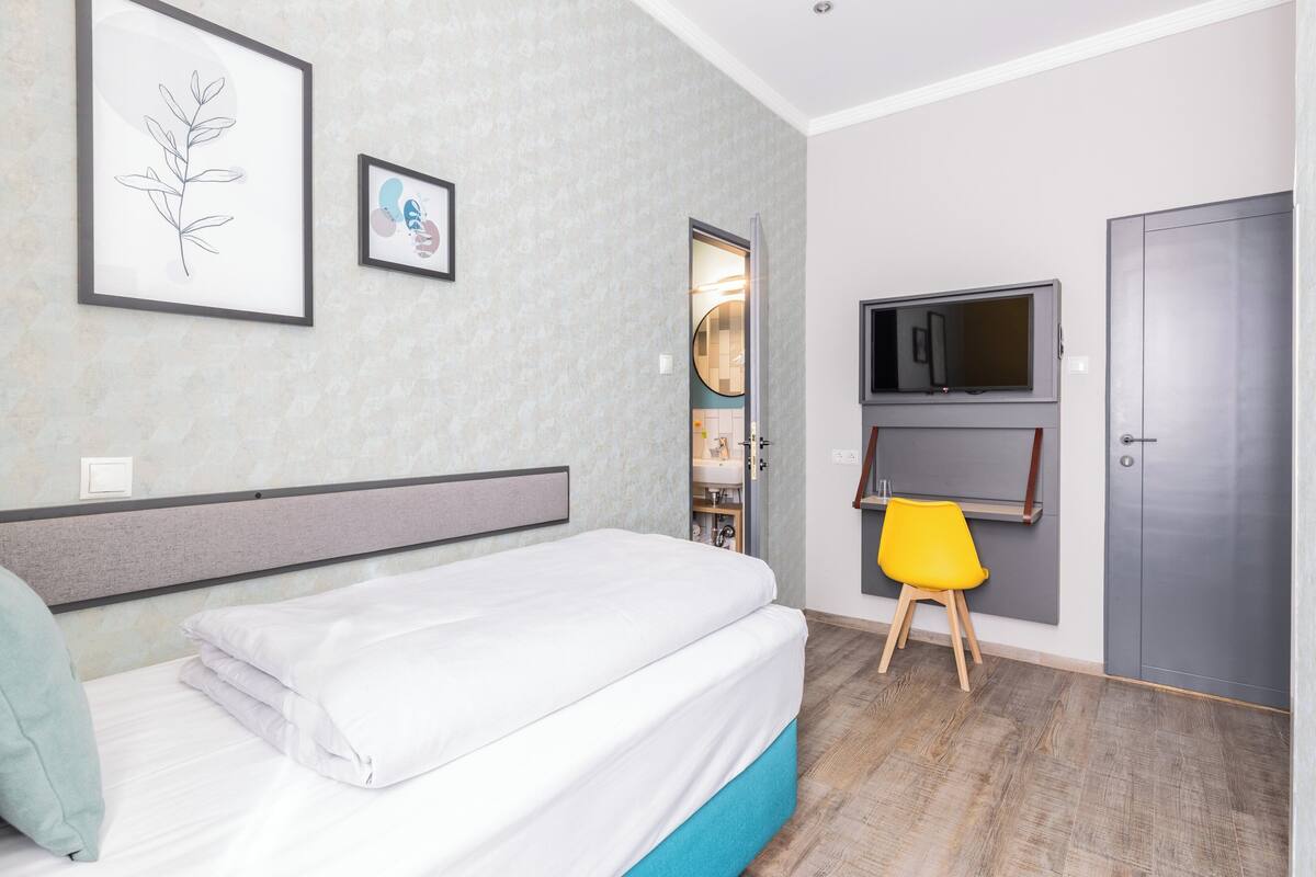 A bedroom with a bed, a chair, a TV, and a wardrobe.