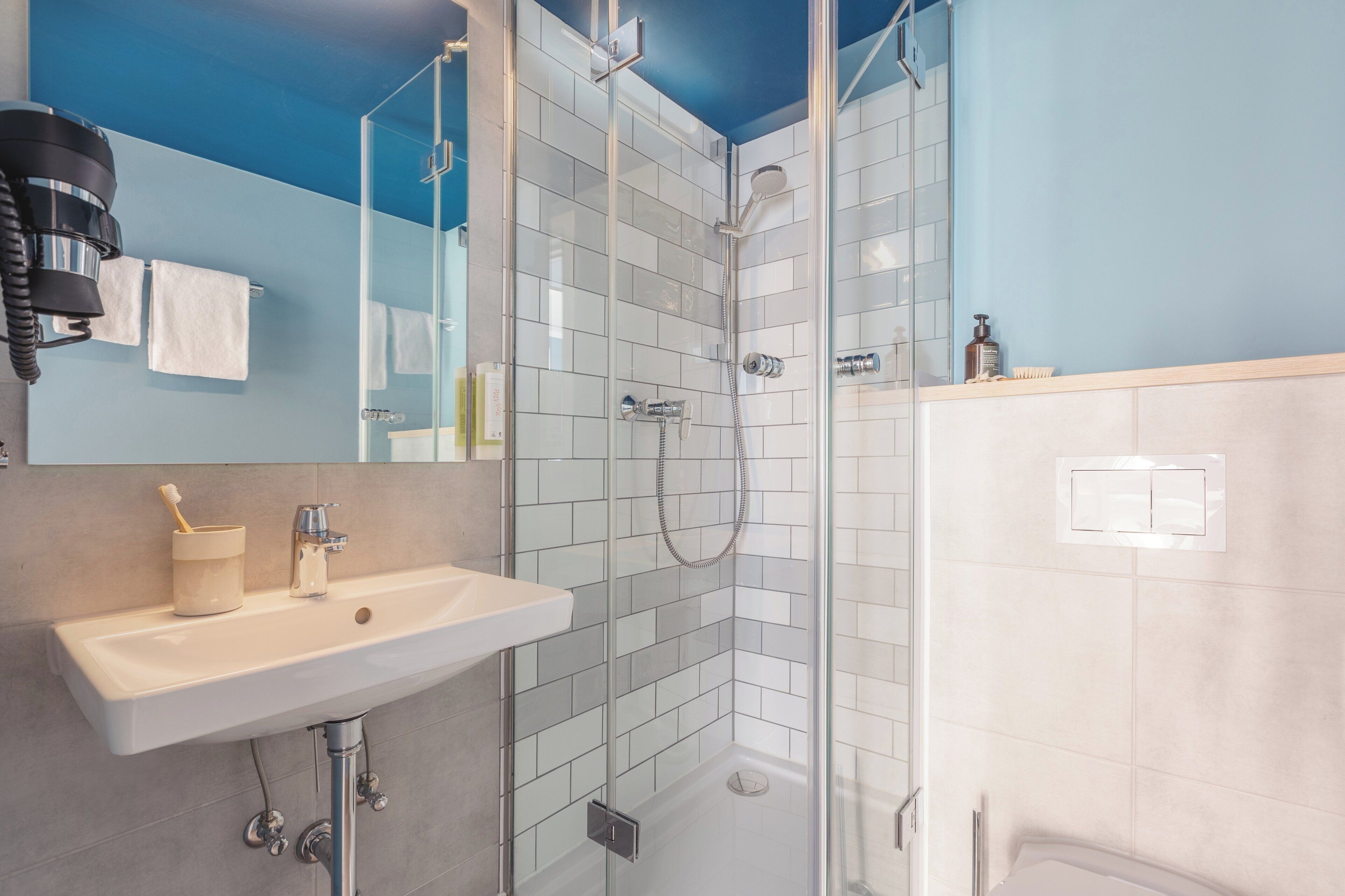 A modern bathroom with a glass-enclosed shower, a sink, and a mirror.