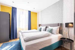 A hotel room with two beds, a desk, a flat-screen TV, and a window with curtains. - Garner Hotel Vienna by IHG (Vienna)