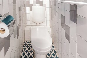 A modern bathroom with a white toilet, geometric tile wall, and black and white floor tiles.