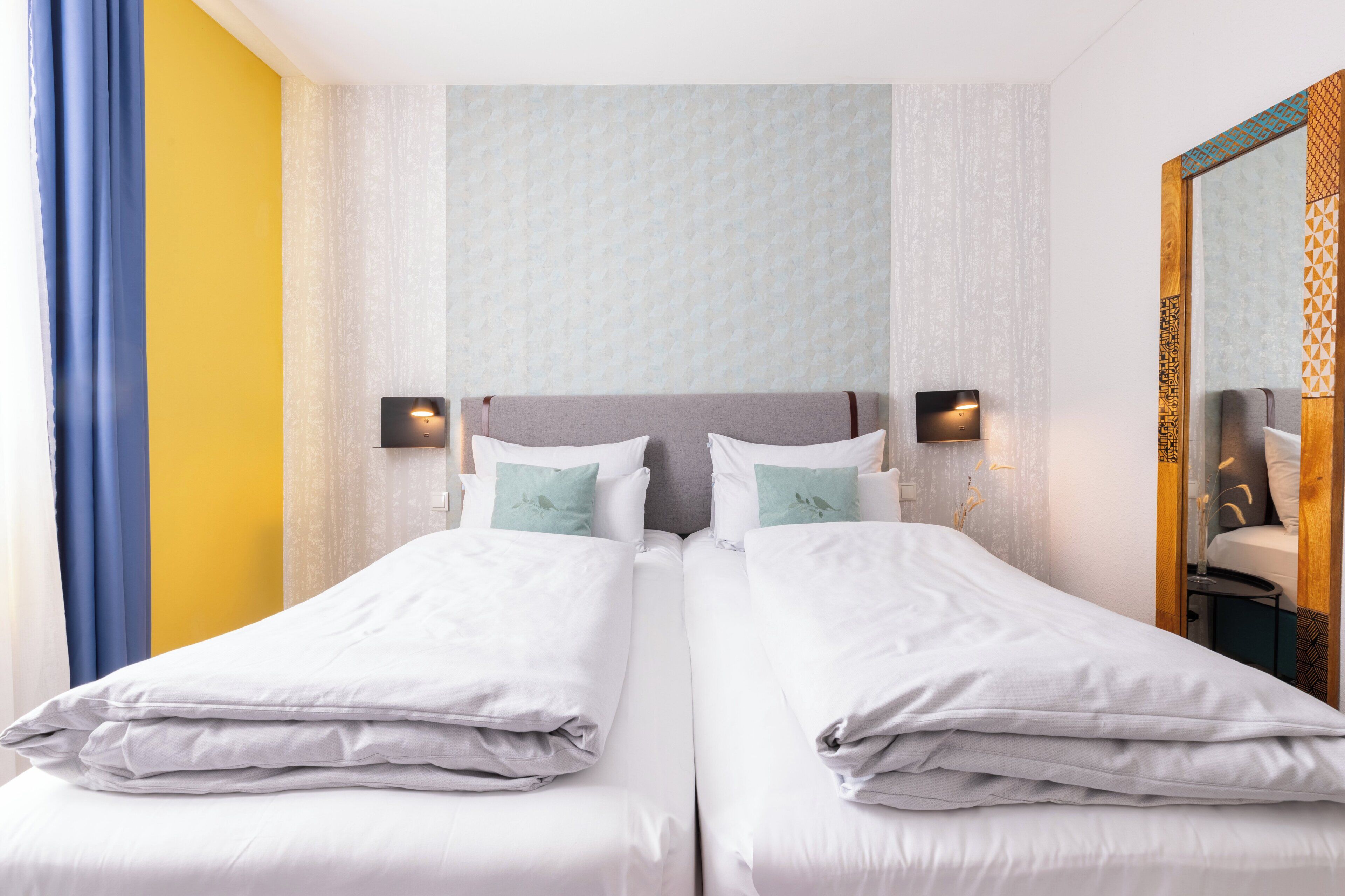 Un lit double avec du linge de lit blanc, deux oreillers et deux tables de chevet avec des lampes.