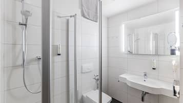 Een moderne badkamer met een douchecabine van glas, een witte wastafel en een toilet.