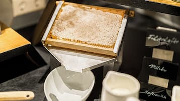 Un panal con un cucharón de miel y un cuenco de cerámica blanca sobre una encimera de cocina.