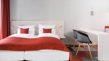 Una habitación de hotel con una cama, un escritorio y una silla.