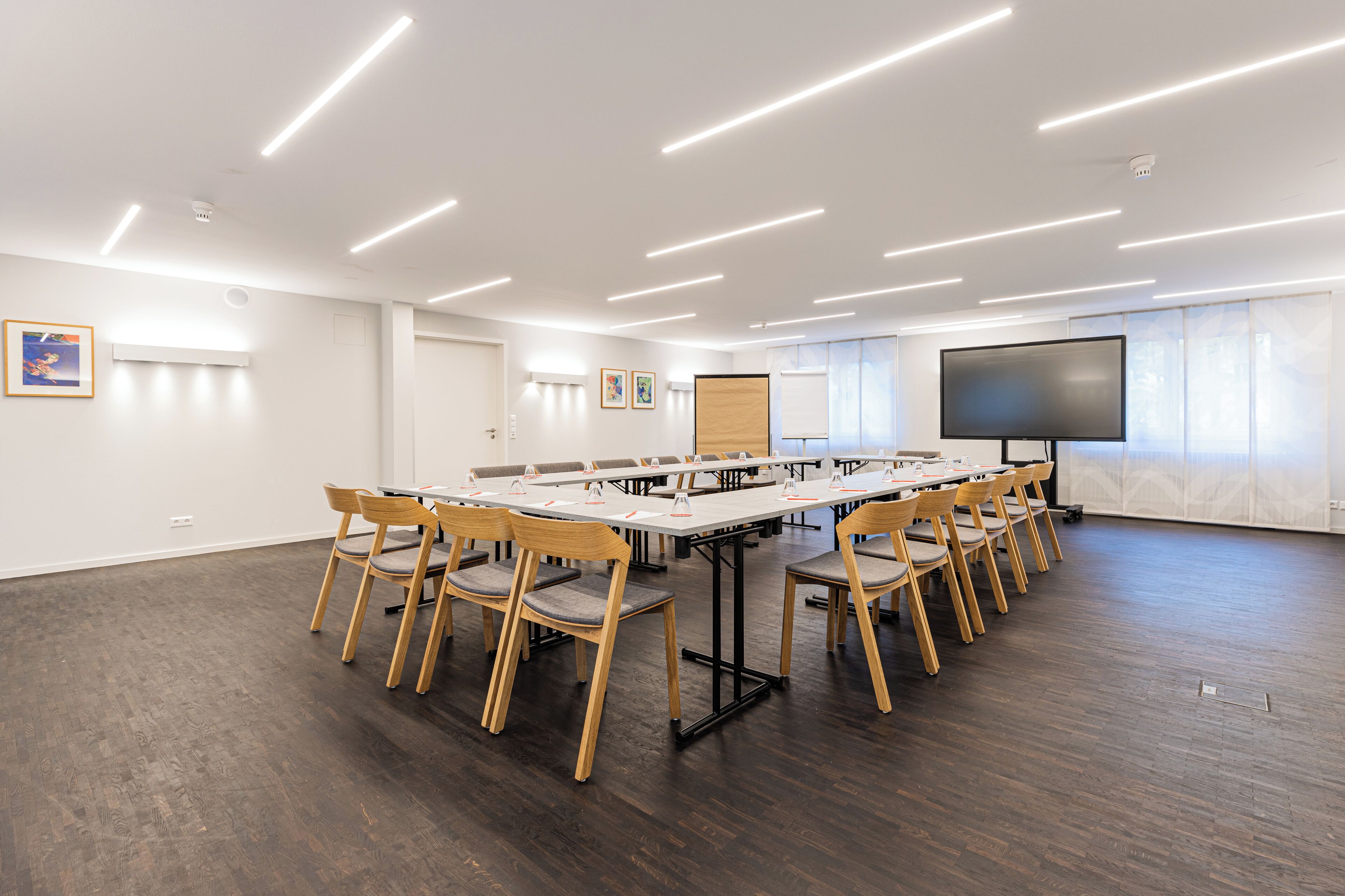 A conference room with a long table, chairs, a projector screen, and a whiteboard.