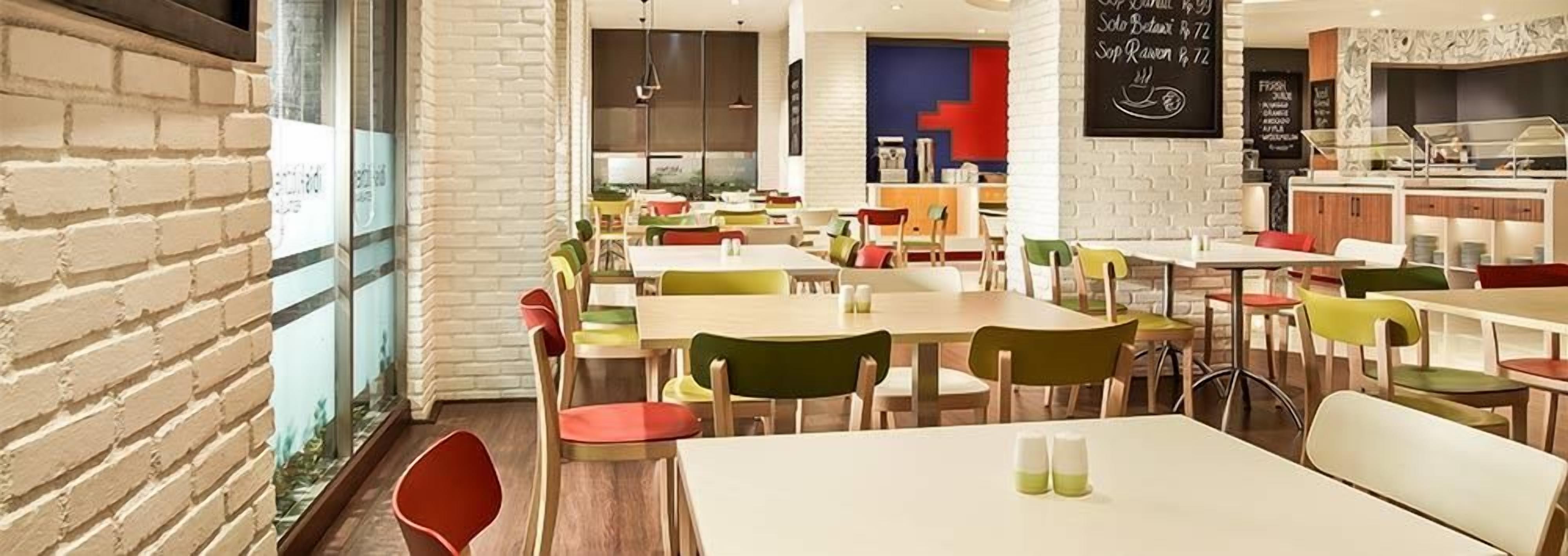 A restaurant with multiple tables and chairs, a brick wall, and a counter area.