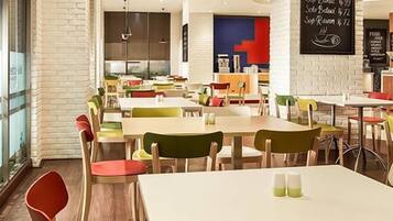A restaurant with multiple tables and chairs, a brick wall, and a counter area.