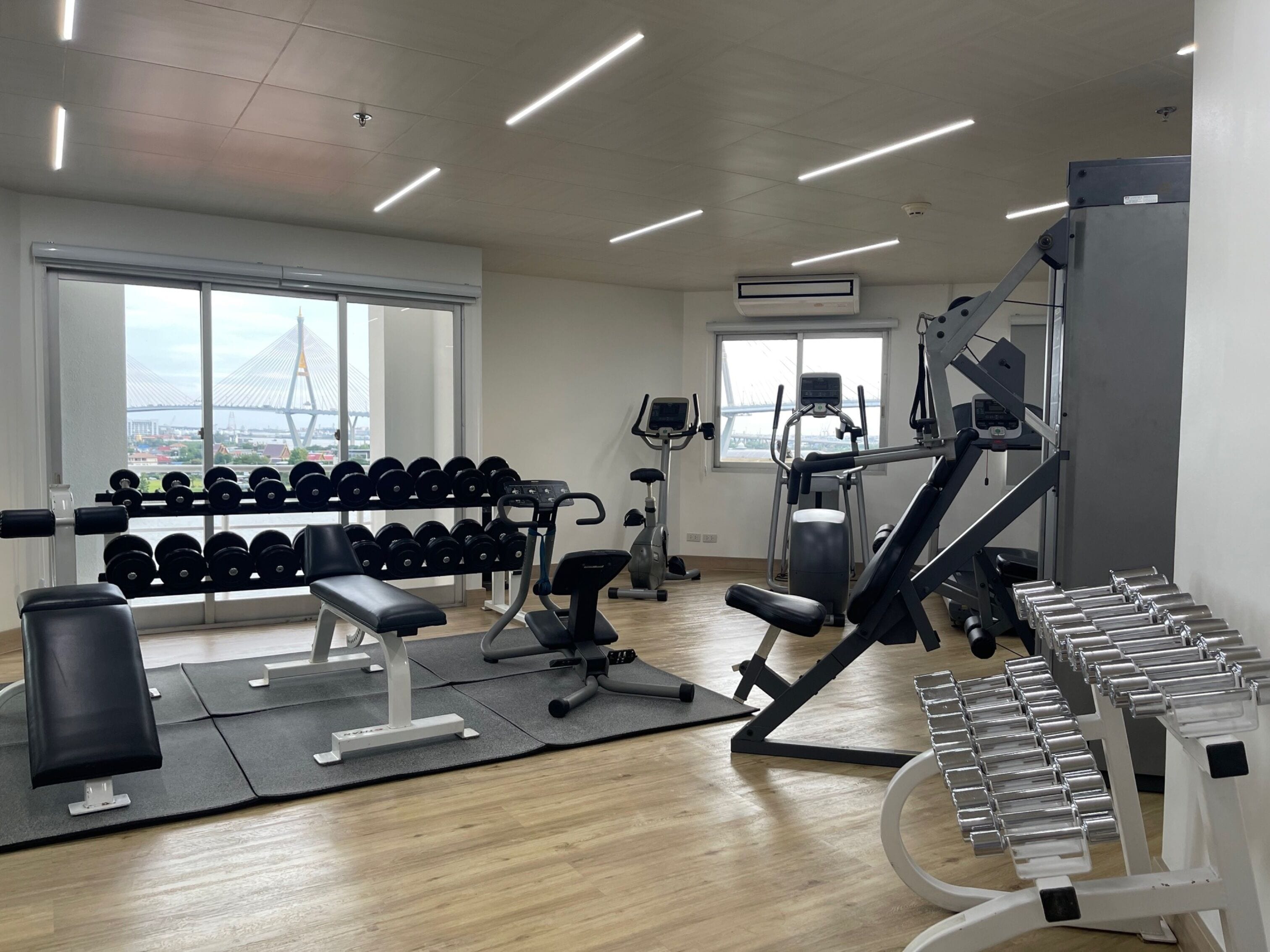 Une salle de sport équipée de machines d’exercice, d’haltères et d’un banc.