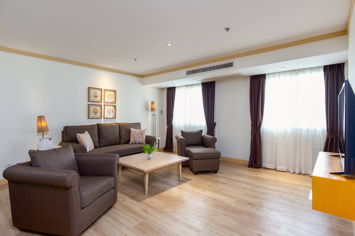 A modern living room with a sofa, armchair, coffee table, and a flat-screen TV.