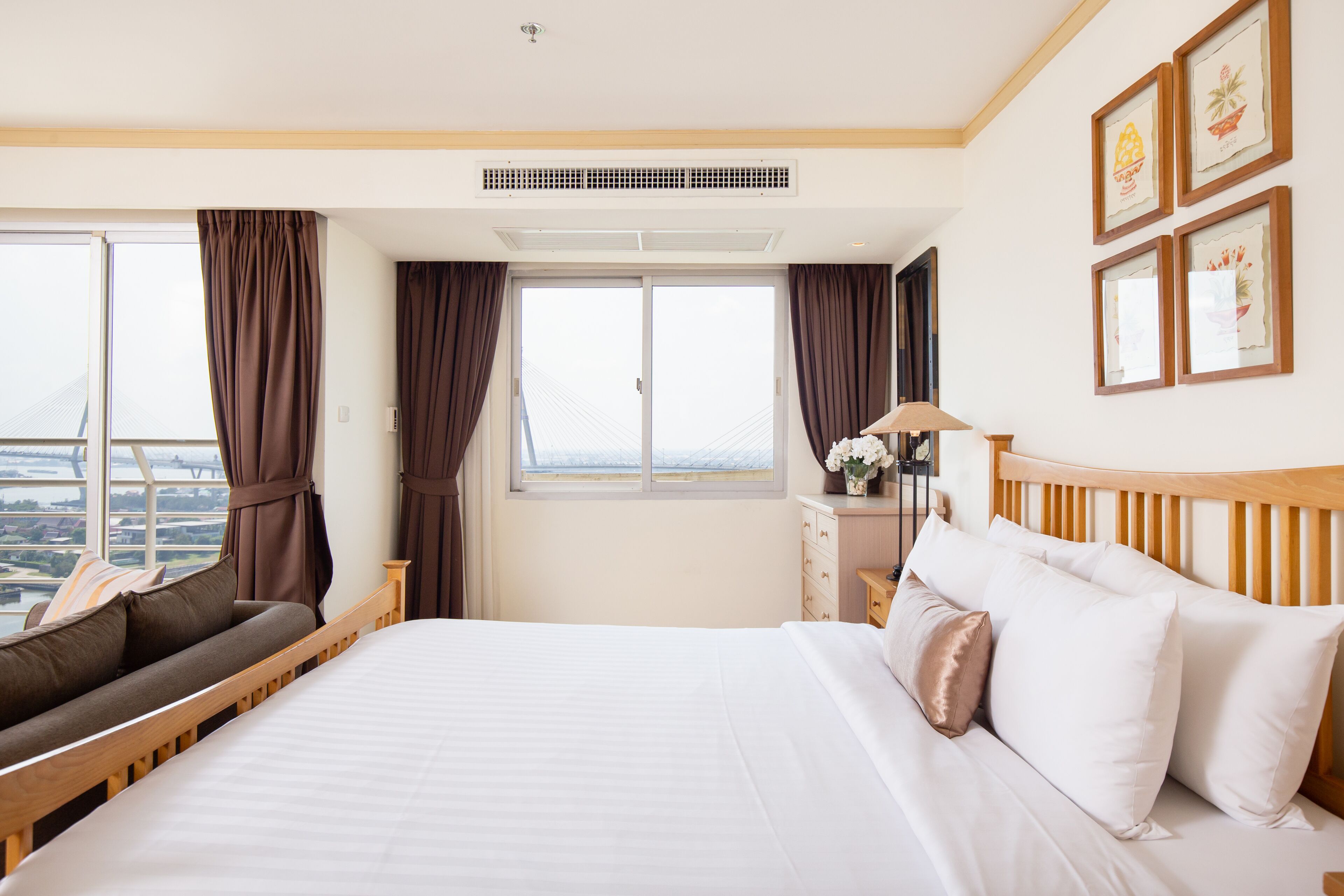 Habitación de hotel con una cama grande, un sofá, un escritorio con lámpara y vistas a la ciudad desde la ventana.