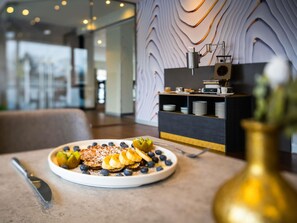 A breakfast setting with a plate of pancakes, blueberries, and sliced bananas. - ibis Berlin Mitte (Berlin)
