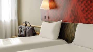 Une chambre d’hôtel avec un lit, des oreillers, une lampe et un sac à main.