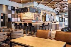 A modern bar area with a brick wall, hanging lights, and a menu board. There are bar stools and a seating area with leather chairs. - Scandic Lahti City (Lahti)