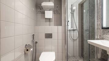 A modern bathroom with a toilet, a glass-enclosed shower, and a sink.