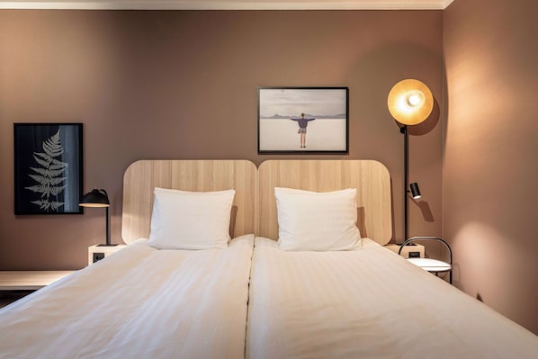 A double bed with white linens, a framed artwork above it, and a bedside table with a lamp. - Scandic Lahti City (Lahti)