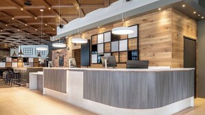 A modern reception area with a curved counter, wooden wall panels, and pendant lighting. - Scandic Lahti City (Lahti)