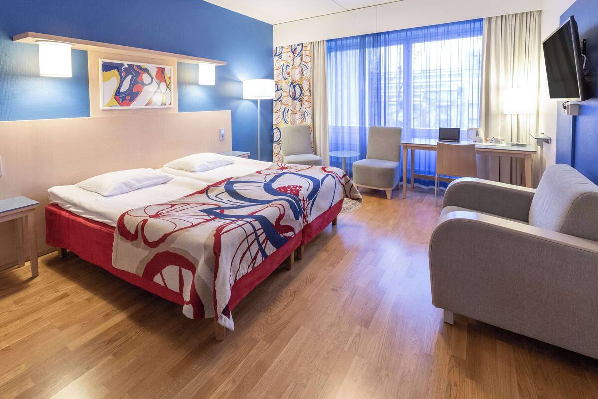 Habitació d'hotel amb un llit gran, una taula, una cadira i una televisió.