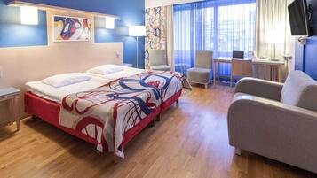 Ein Hotelzimmer mit einem großen Bett, einem Schreibtisch, einem Stuhl und einem Fernseher.