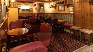 Un interior de restaurante acogedor con paredes de madera, suelo escocés y asientos tapizados en rojo.